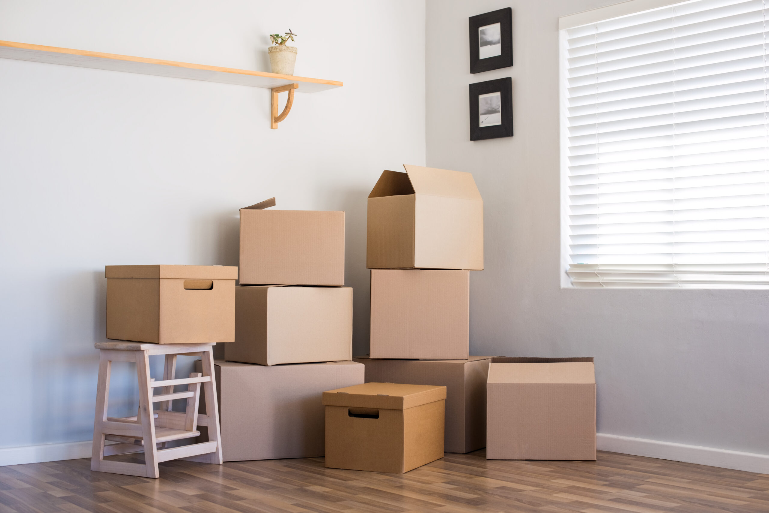 Stack of cardboard boxes in an empty room. Pile of carton boxes on the floor in an empty apartment. Stack of moving boxes in new house.